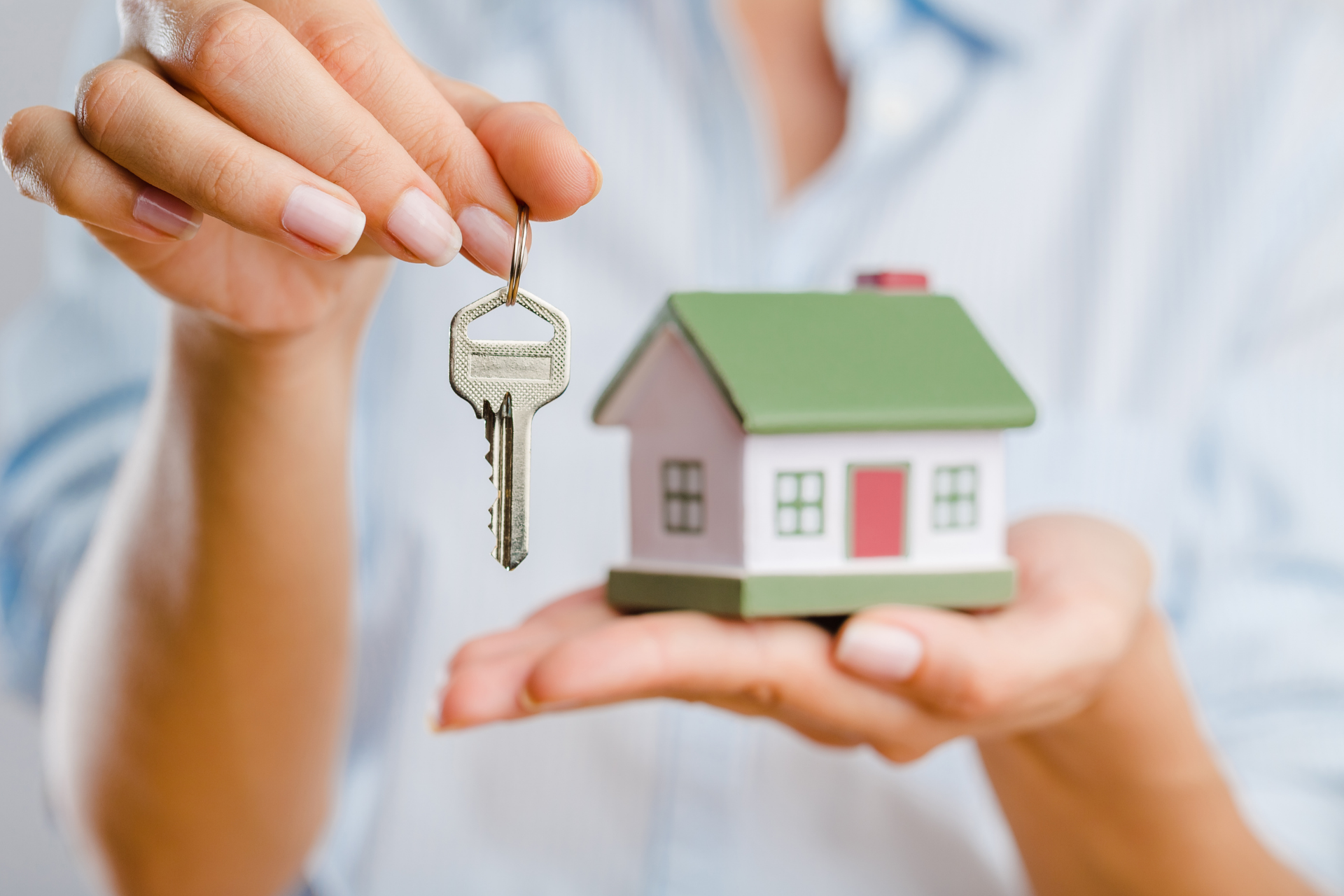 woman holding house key and miniature home